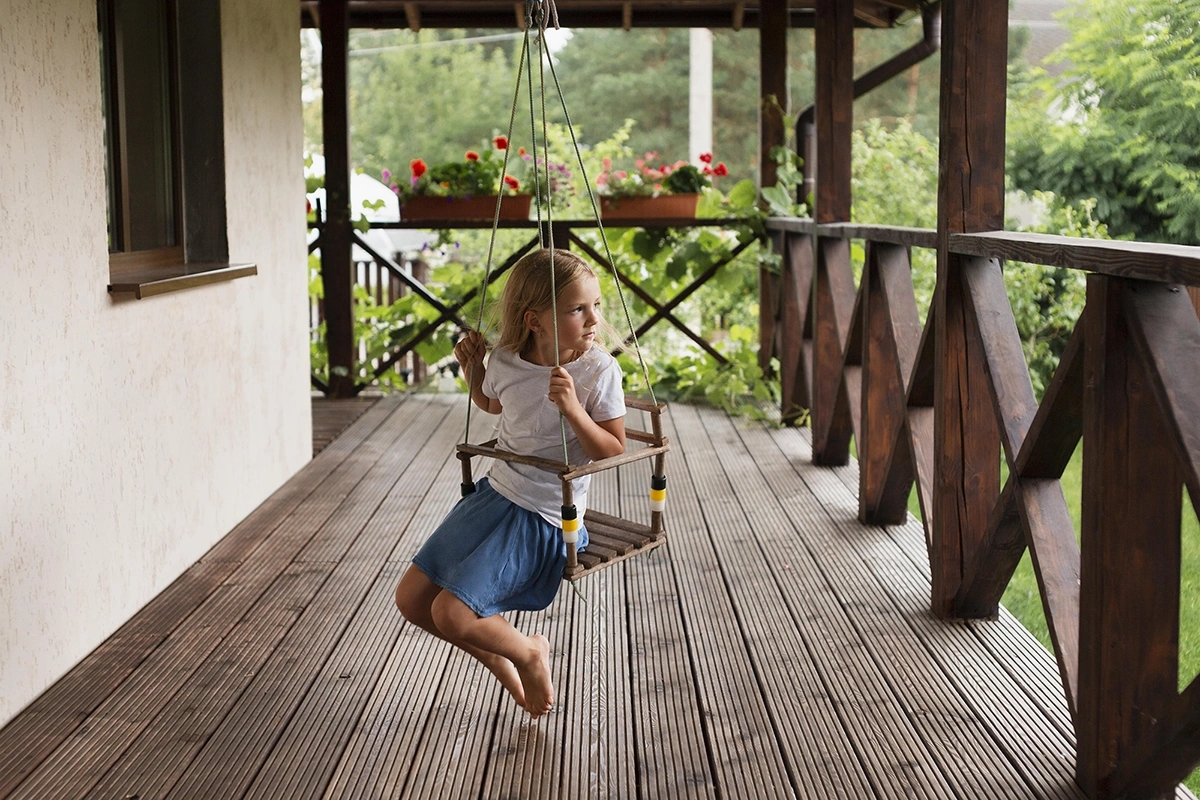Child on a wooden swing on a rustic deck – Trent Hills deck repair experts