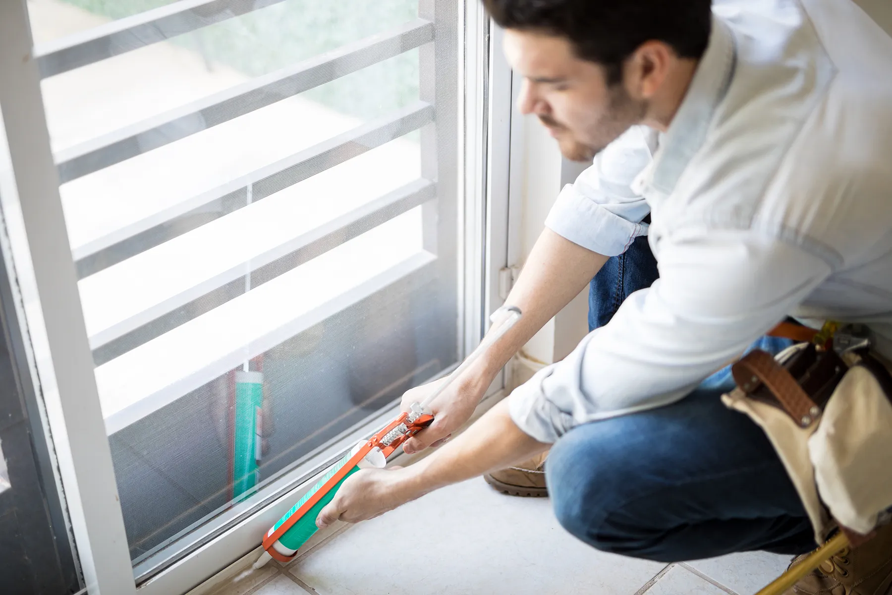 Renossance professional sealing a window frame to prevent drafts and improve efficiency - true cost of window installation.