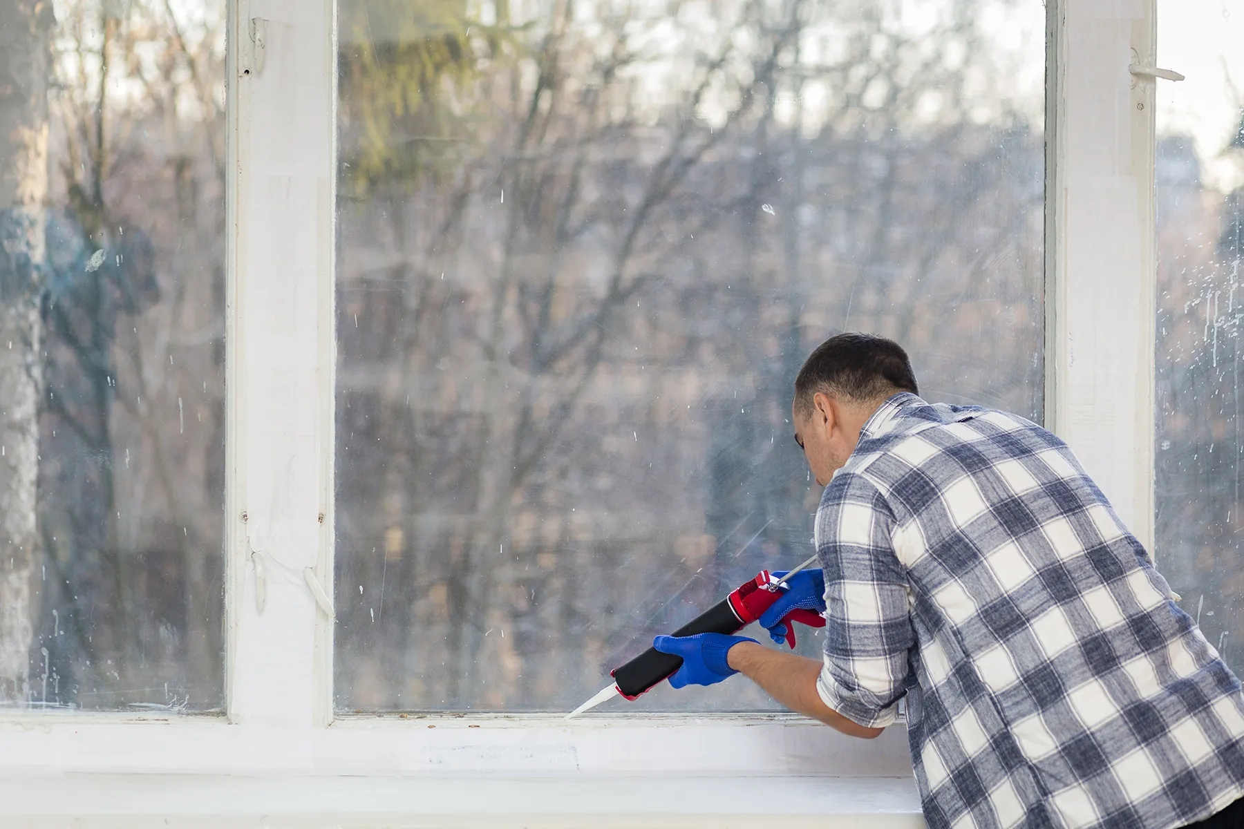 Renossance technician performing precise sealing during window repair or replacement for energy efficiency.