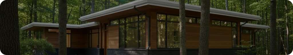 Seamless eavestrough on a modern mid-century style house with wood cladding and panoramic windows, nestled among tall trees in a lush green forest