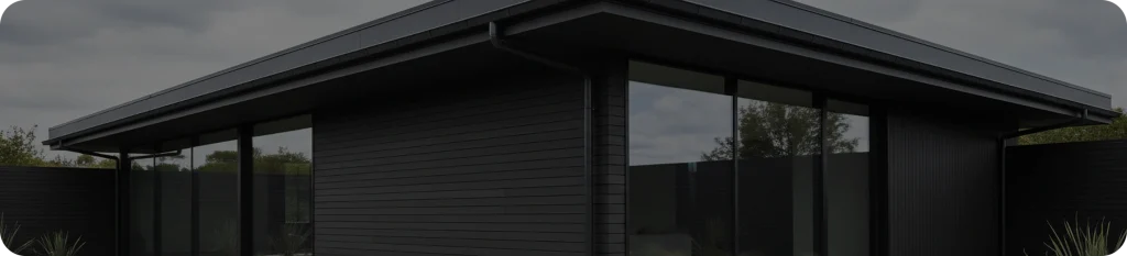 22:30Seamless eavestrough on a contemporary all-black flat-roof house with floor-to-ceiling windows and dark horizontal siding under an overcast sky