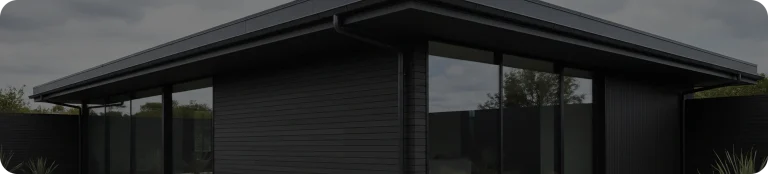 22:30Seamless eavestrough on a contemporary all-black flat-roof house with floor-to-ceiling windows and dark horizontal siding under an overcast sky