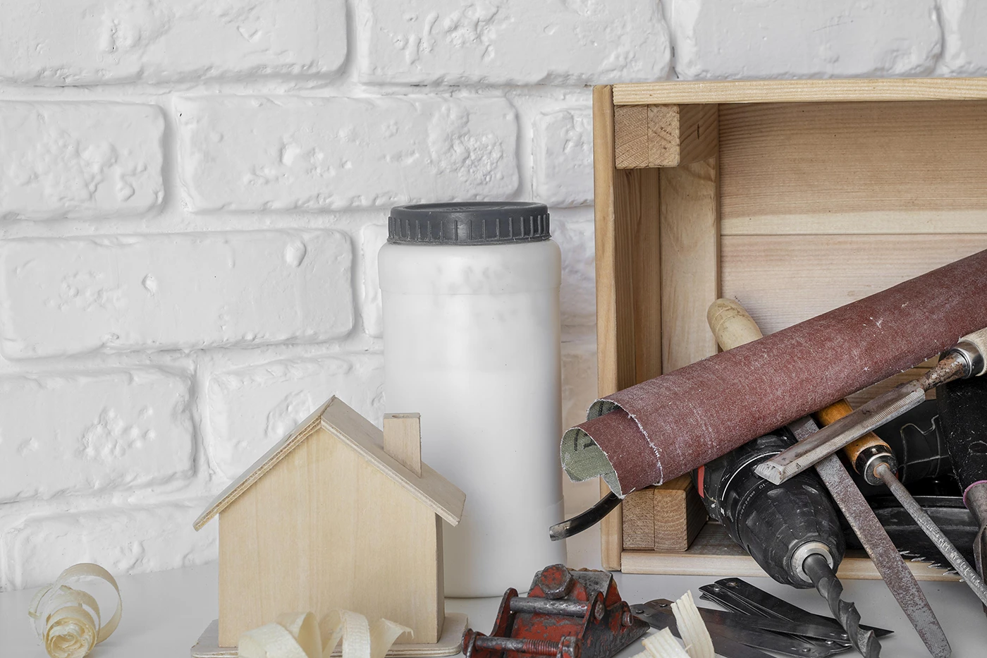 General home repair services tools and materials displayed beside a small wooden house model.