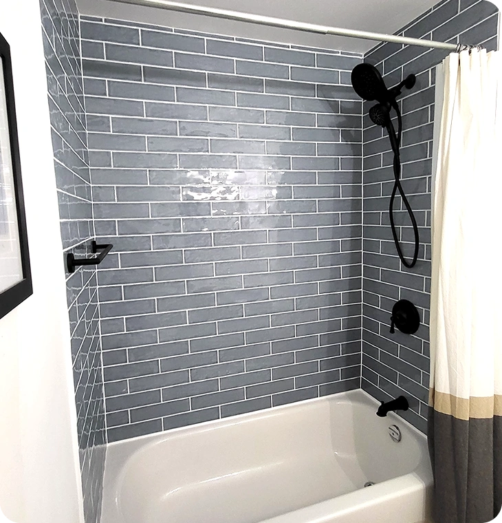 White bathtub with dark shower tile and matte black fixtures – Bathroom Renovations Norwood, ON by Renossance