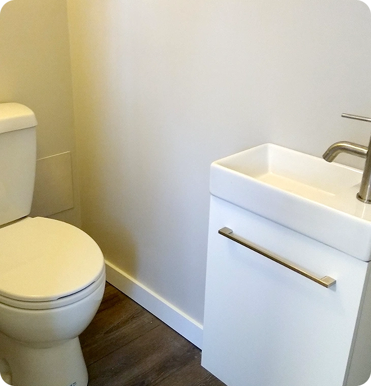 Small powder room with white vanity and wood-look flooring – Bathroom Renovations Hastings, ON by Renossance