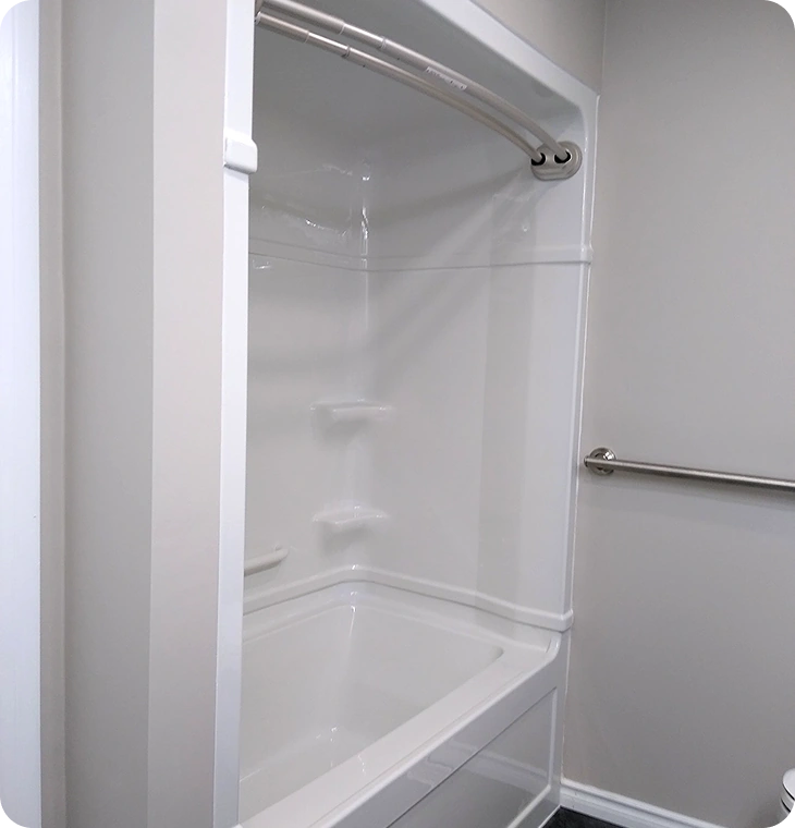 Clean white tub and shower combo with safety grab bar – Bathroom Renovations Madoc, ON by Renossance