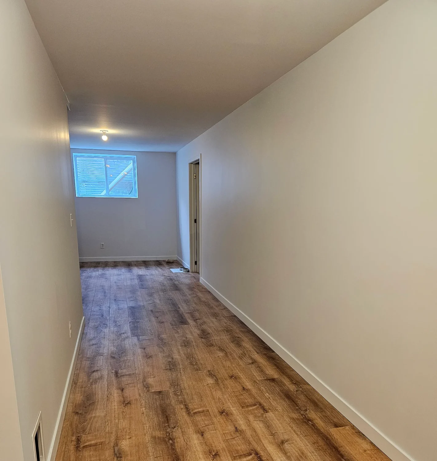 Freshly painted light gray hallway and basement room in Marmora home by Renossance
