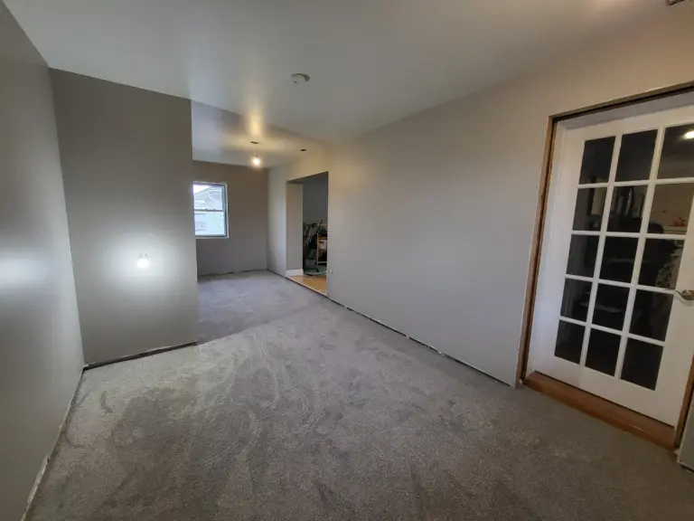 Light grey painted walls and white ceiling in a carpeted room with a glass-panel French door, interior painting by Renossance